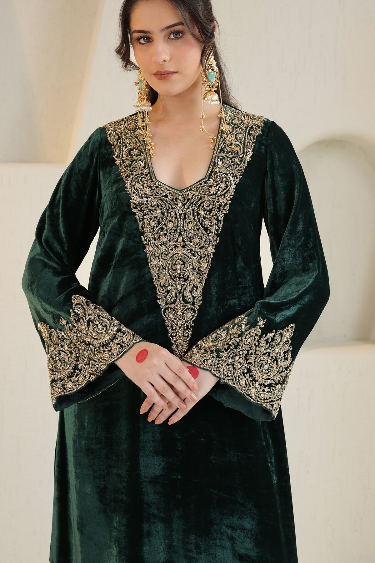 A rich emerald velvet ensemble adorned with intricate antique-gold embroidery.