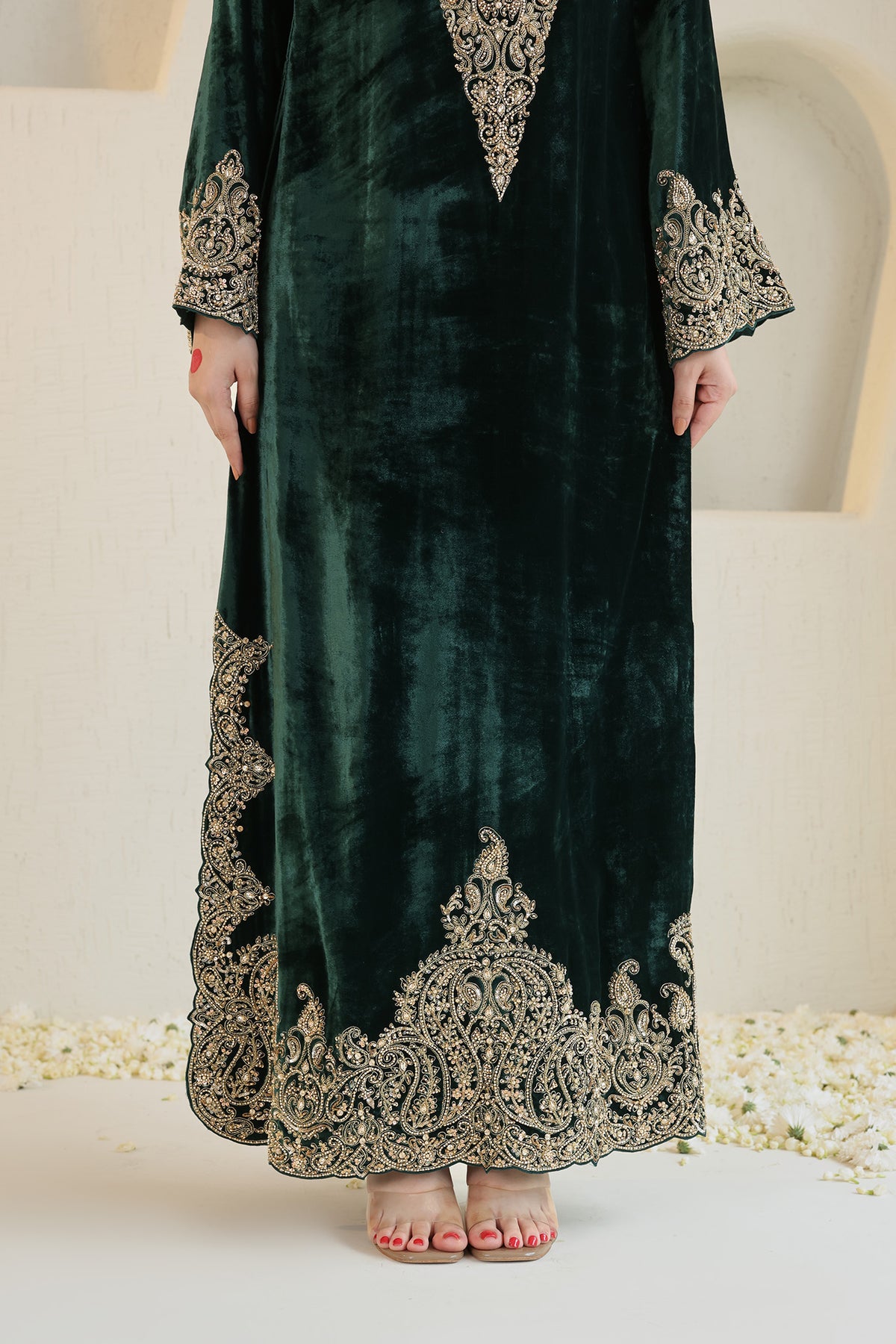A rich emerald velvet ensemble adorned with intricate antique-gold embroidery.